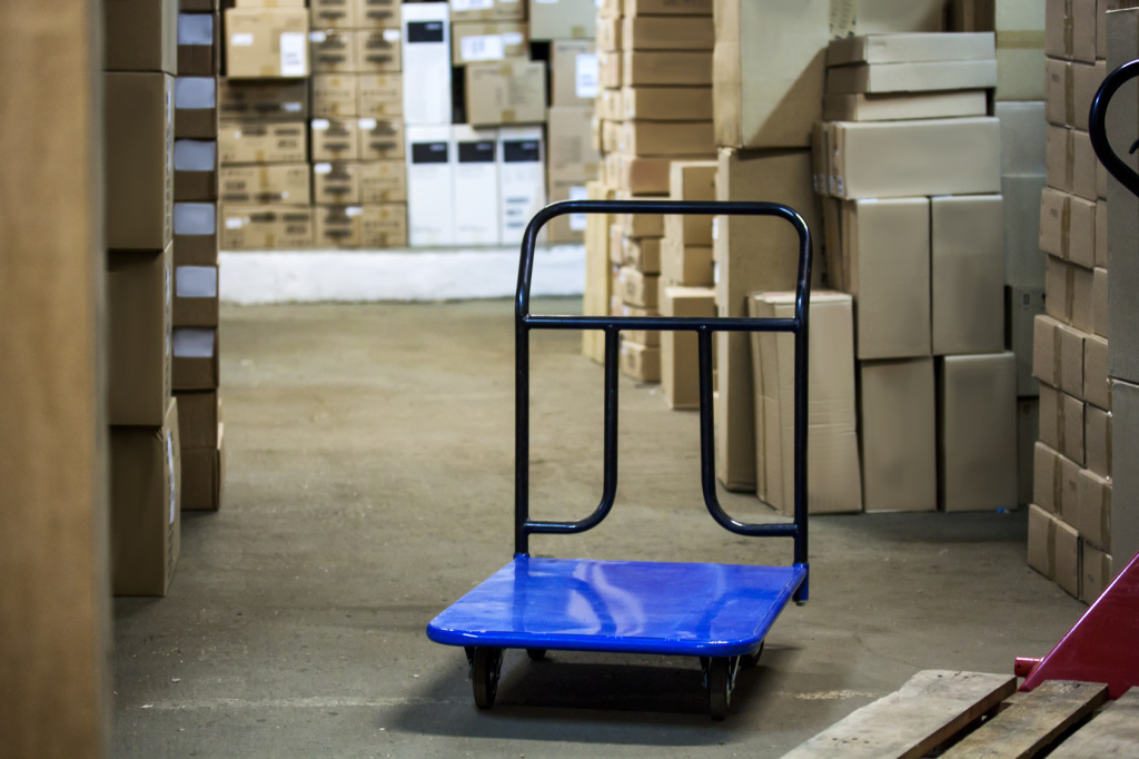 Warehouse with goods in boxes and trolleys for transportation of goods close-up